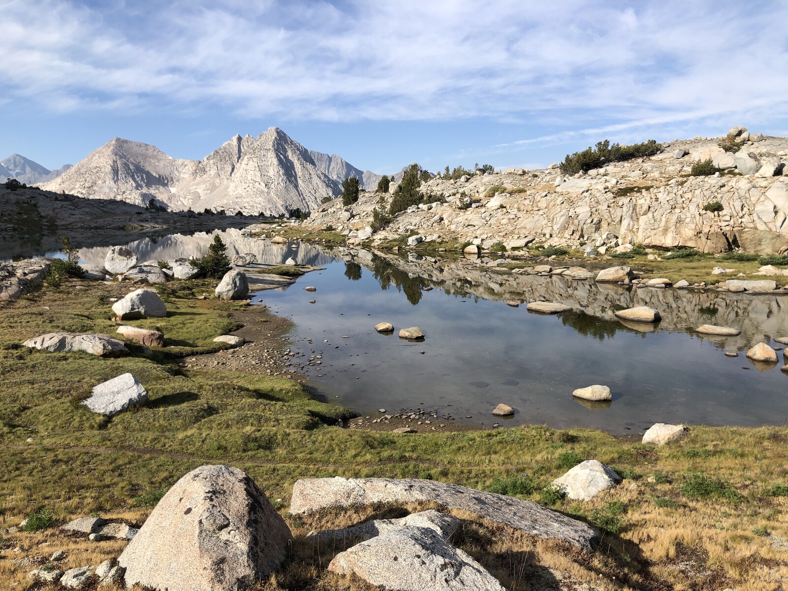 Scenic alpine meadow with calm reflecting pool and distant peaks