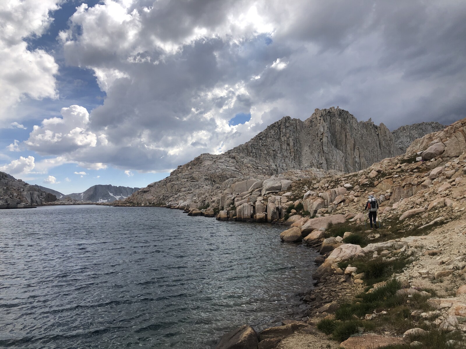 Boulder-lined alpine lake shore with columnar rock walls
