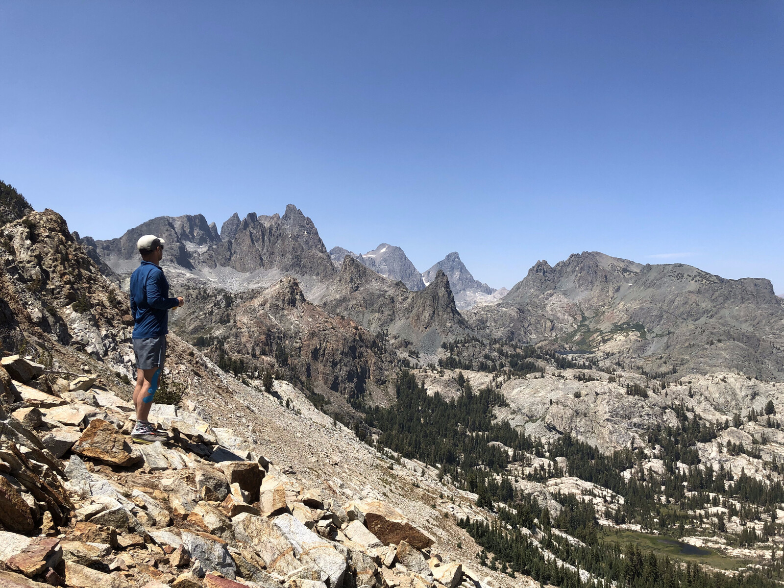 Hiker on overlook with expansive alpine valley view