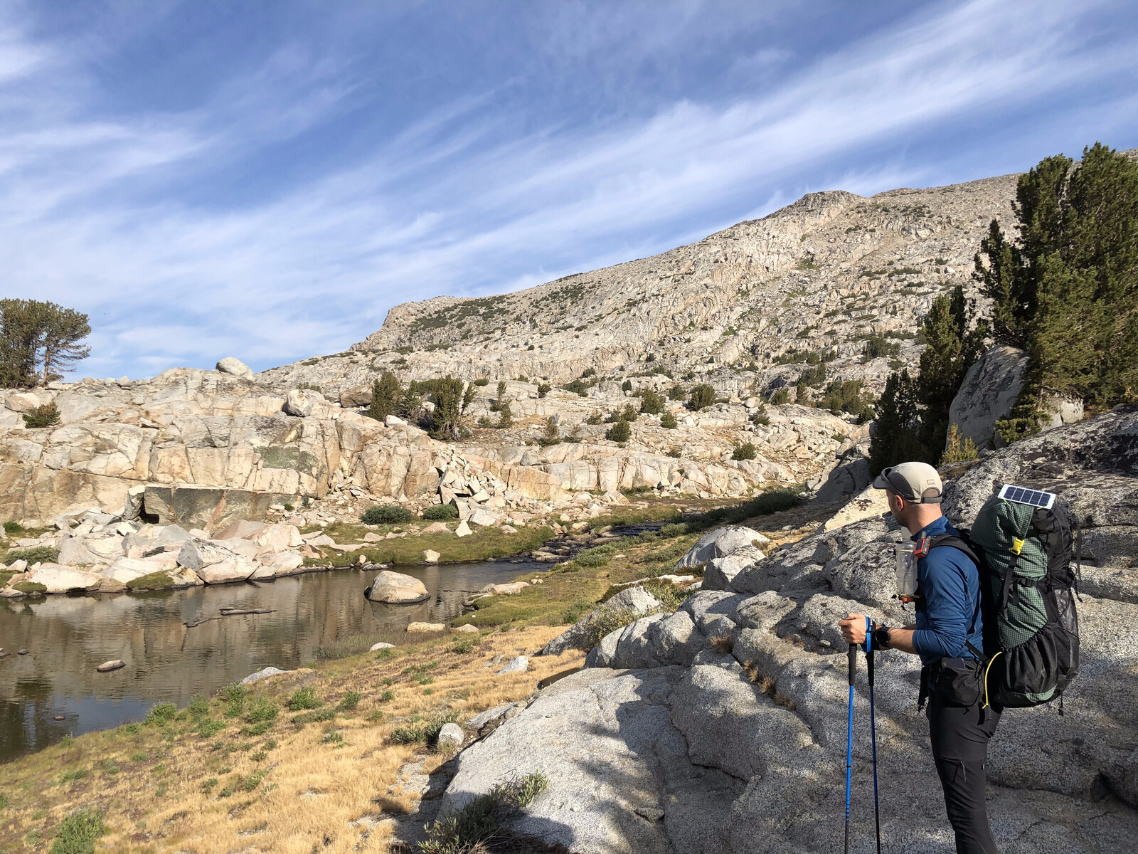 Hiker on boulder beside turquoise alpine lake with dramatic peaks